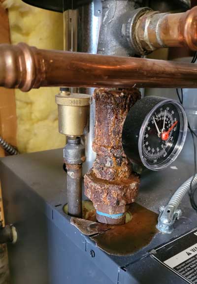 Rust and moisture covering a fitting going into a home boiler heating system