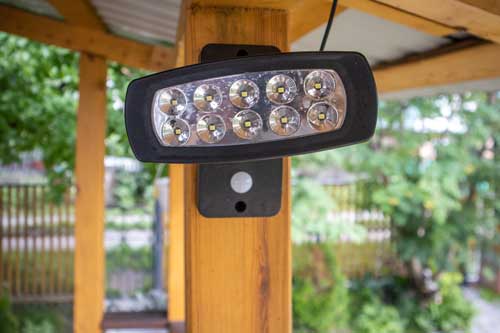 Outdoor LED security spotlight installed on a wooden post for improved safety and visibility