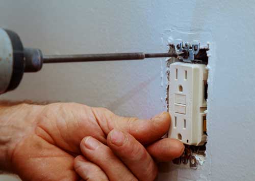 Electrician installing a GFCI outlet to bring a home up to electrical code