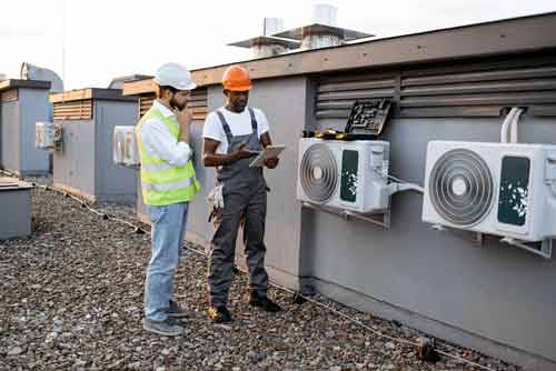 Technicians analyzing ac units on the roof of a building
